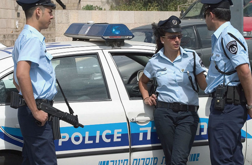 Police chat near a patrol car  (photo credit: MARK PROBST / WIKIMEDIA COMMONS)