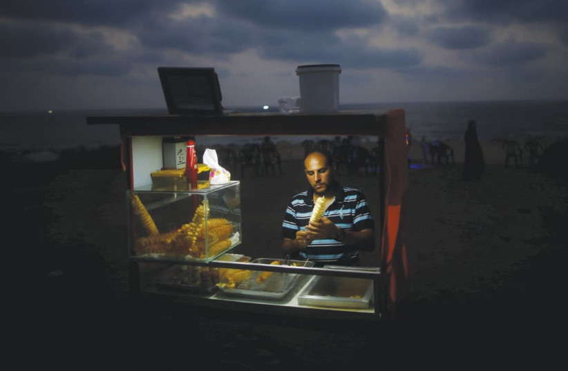 A vendor sells snacks on a beach during a power cut in Gaza City in summer of 2017 (photo credit: MOHAMMED SALEM/REUTERS)
