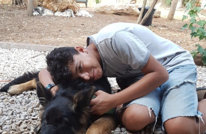 Lidor, a member of the Hadassah Ne'urim Youth village, poses with one of the dogs being rehabilitated at the site. (photo credit: Courtesy)
