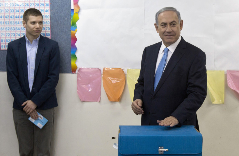 Yair Netanyahu observes his father Israeli Prime Minister Benjamin Netanyahu casting a ballot in the 2015 elections. (photo credit: REUTERS/SEBASTIAN SCHEINER/POOL)
