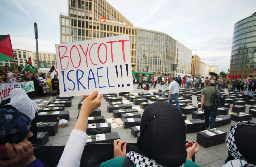 A WOMAN holds a ‘Boycott Israel’ sign in front of symbolic cof ns while attending a demonstration in 2014 supporting Palestine, in Berlin (photo credit: STEFFI LOOS /REUTERS)