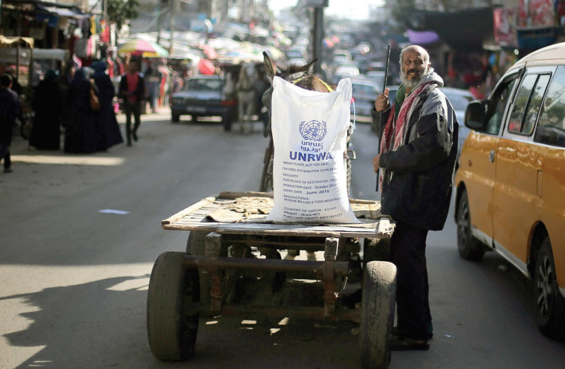 A MAN STANDS next to a cart carrying a sack of flour distributed by UNRWA in the Khan Yunis refugee camp in the Gaza Strip in January, 2018. (photo credit: IBRAHEEM ABU MUSTAFA / REUTERS)