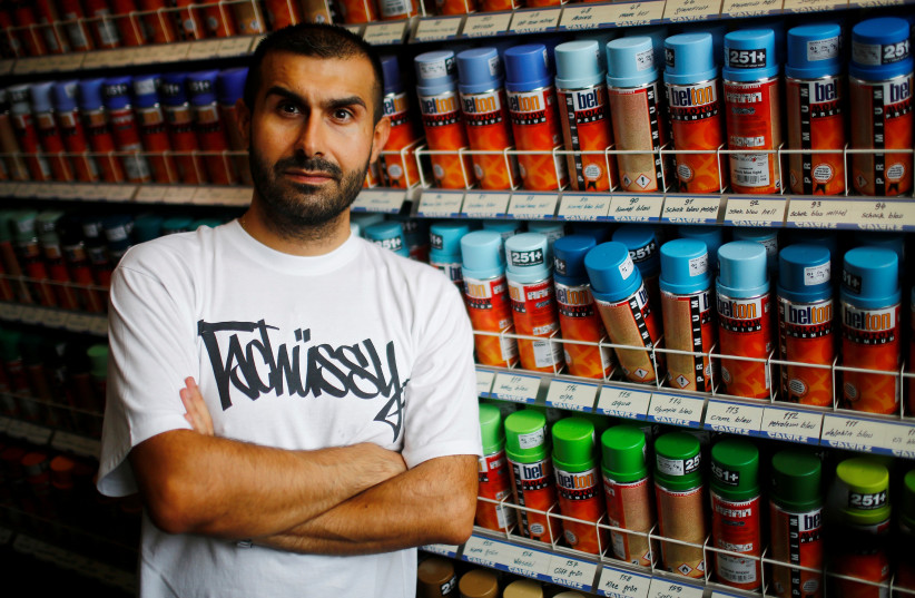 Graffiti artist Ibo Omari poses for a portrait in his shop in Berlin, Germany August 18, 2017.  (photo credit: HANNIBAL HANSCHKE/REUTERS)
