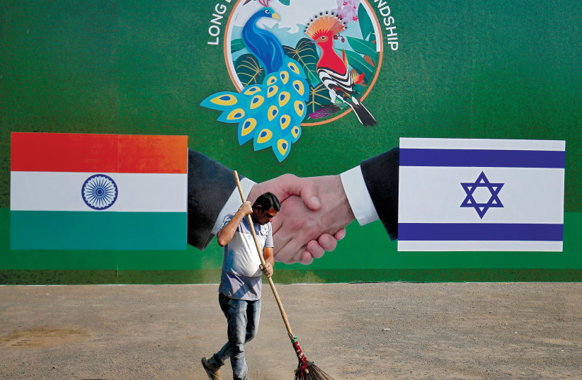 A municipal worker cleans the street in front of a bilboard displaying Indian and Israeli flags for PM Netanyahu's visit, Ahmedabad, India, January 2018 (photo credit: REUTERS/AMIT DAVE)