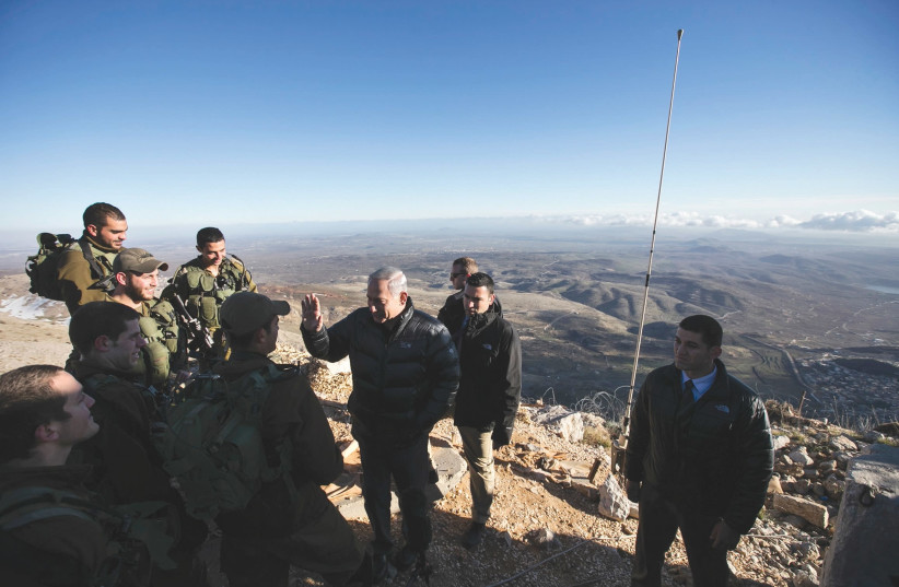 PRIME MINISTER Benjamin Netanyahu chats with Israeli soldiers at a military outpost during a visit to Mount Hermon in the Golan Heights overlooking the Israel-Syria border in 2015. (photo credit: REUTERS/BAZ RATNER)