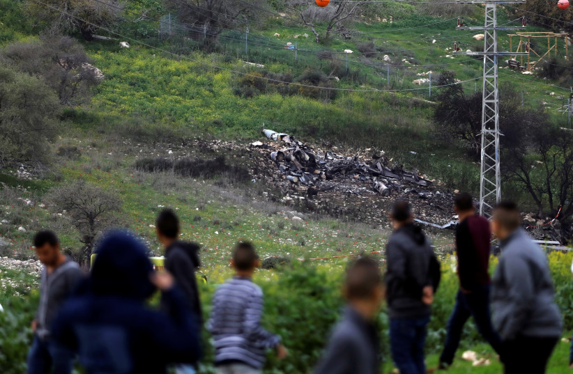 Bystanders look on at the remnants of an Israeli F-16 fighter jet shot down by Syrian forces, February 2018 (photo credit: RONEN ZVULUN/ REURERS)