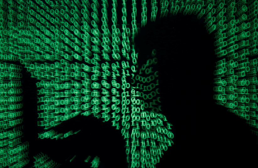 A man holds a laptop computer as cyber code is projected on him (photo credit: KACPER PEMPEL/REUTERS)