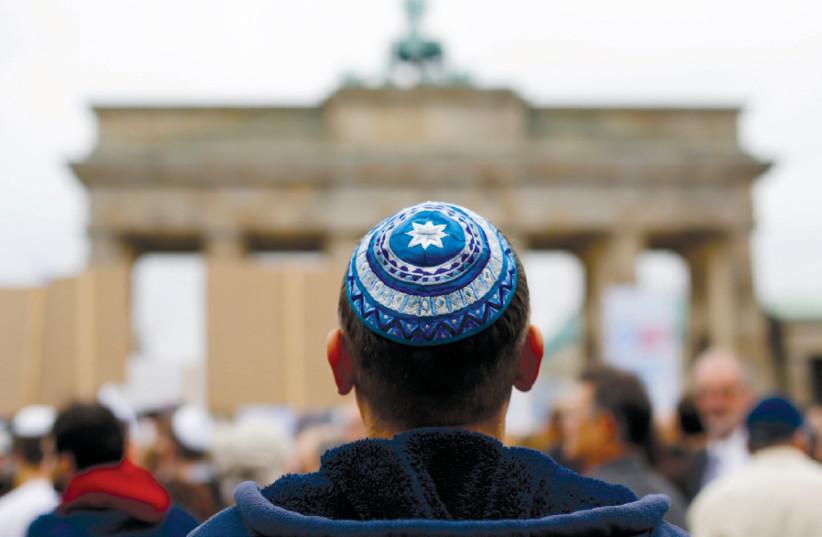 A MAN wearing a kippa waits for the start of a demonstration against antisemitism at Berlin’s Brandenburg Gate in 2014 (photo credit: THOMAS PETER/REUTERS)