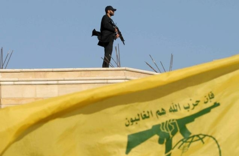 A Hezbollah member carries his weapon on top of a building on May 25, 2016. (photo credit: HASSAN ABDALLAH / REUTERS)