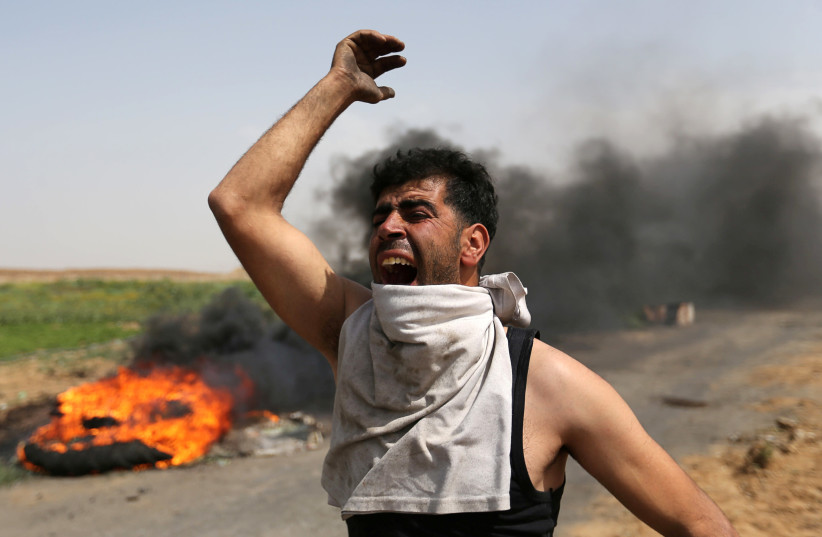 A Palestinian shouts during clashes along the Israel border with Gaza ahead of a protest in the southern Gaza Strip March 29, 2018. (photo credit: REUTERS/IBRAHEEM ABU MUSTAFA)