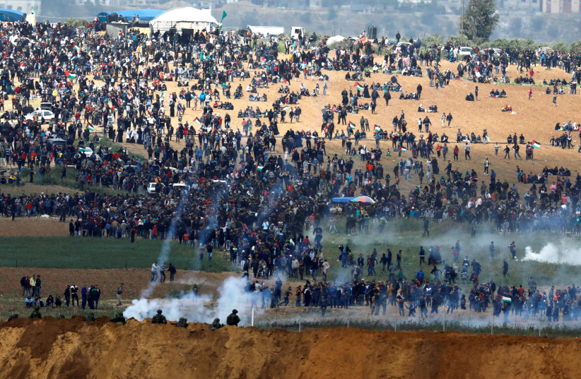 Israeli soldiers shoot tear gas from the Israeli side of the Israel-Gaza border, as Palestinians protest on the Gaza side of the border, March 30, 2018. (photo credit: AMIR COHEN/REUTERS)
