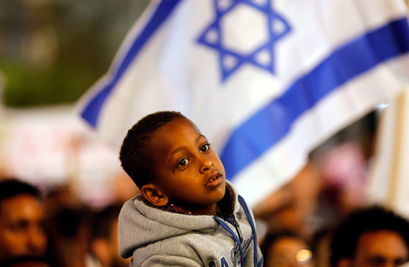 A boy takes part in a protest against the Israeli government's plan to deport African migrants, in Tel Aviv, Israel March 24, 2018. (photo credit: REUTERS/CORINNA KERN)