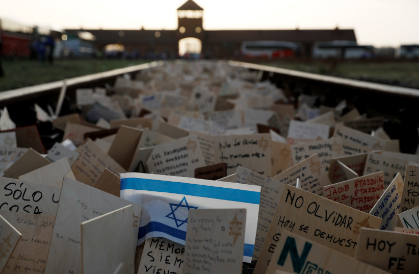 Cards are placed between railway tracks in the former Nazi death camp Auschwitz as people take part in the annual "March of the Living" to commemorate the Holocaust, in Oswiecim, Poland, April 12, 2018.  (photo credit: REUTERS/KACPER PEMPEL)