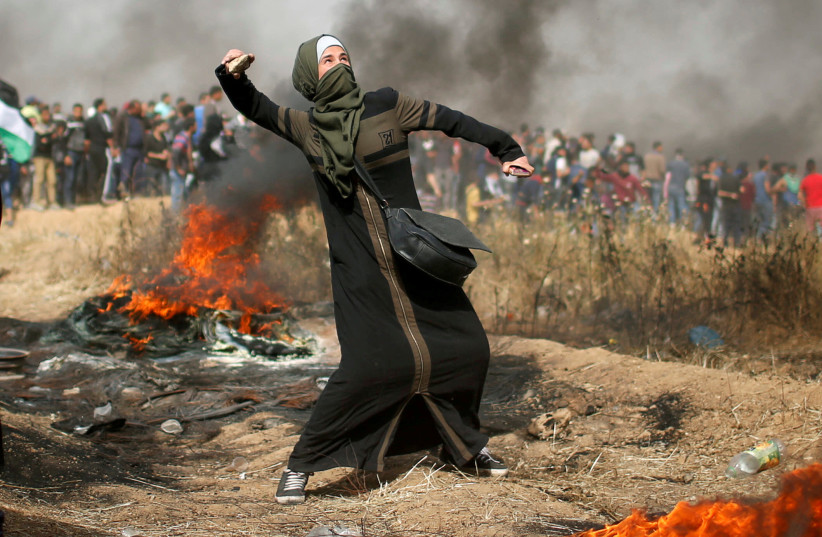 A girl hurls stones during clashes with Israeli troops at a protest at the Israel-Gaza border, east of Gaza City, April 13, 2018 (photo credit: MOHAMMED SALEM/REUTERS)