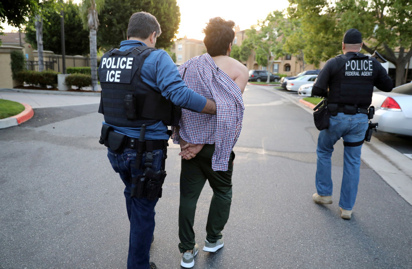 Immigration and Customs Enforcement agents escort an immigrant (photo credit: LUCY NICHOLSON / REUTERS)