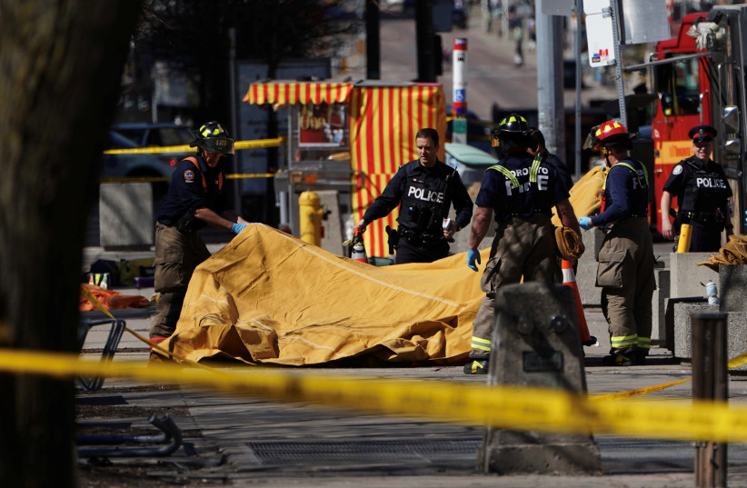 Firemen cover a victim of an incident where a van struck multiple people at a major intersection in Toronto's northern suburbs, in Toronto, Ontario, Canada, April 23, 2018 (photo credit: CARLO ALLEGRI/REUTERS)