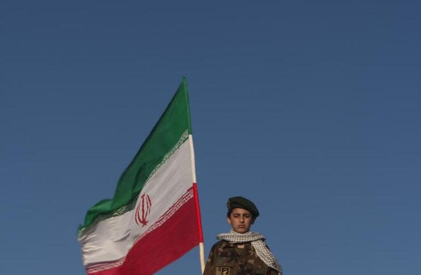  A member of Iran's Revolutionary guard stands guard next to an Iranian flag during an anti-US ceremony in Azadi Square in Tehran, April 25, 2010 (photo credit: REUTERS/MORTEZA NIKOUBAZL)