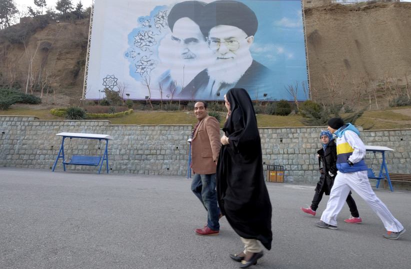 Iranians walk past a large picture of Iran's late leader Ayatollah Ruhollah Khomeini (L), and Iran's Supreme Leader Ayatollah Ali Khamenei at a park in Tehran, Iran, January 17, 2016. (photo credit: RAHEB HOMAVANDI/TIMA VIA REUTERS)