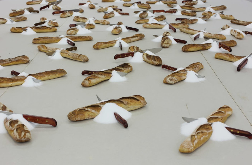 Romanian artist Mircea Cantor’s oversized table filled with baguettes, knives and piles of salt sets the stage for those first entering the gallery (photo credit: Courtesy)