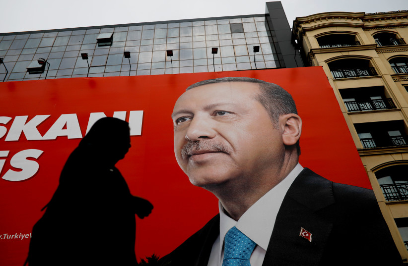 A woman passes by an election poster of Turkey's President Tayyip Erdogan in Istanbul, Turkey (photo credit: ALKIS KONSTANTINIDIS / REUTERS)