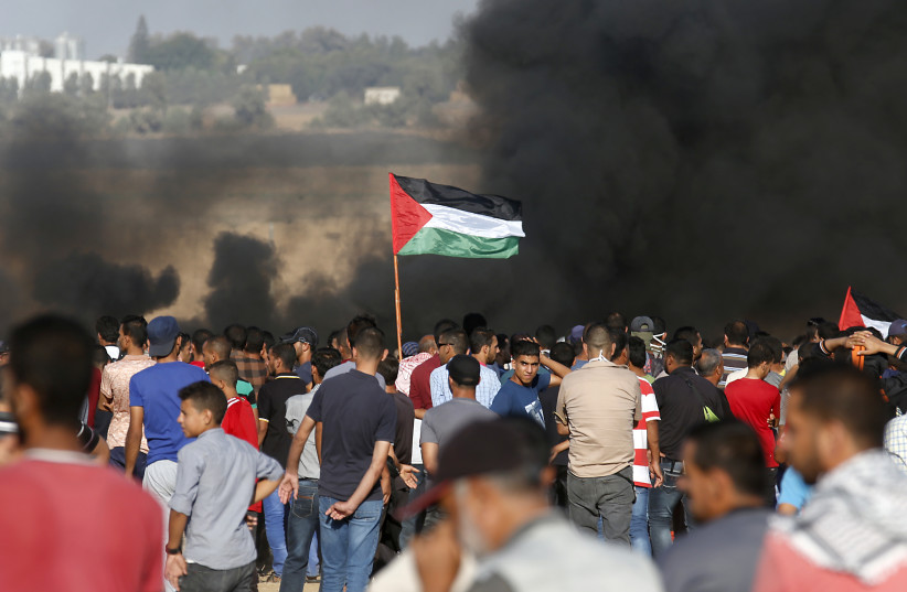 Palestinian protesters wave their national flag as they gather during a demonstration at the Israel-Gaza border, in Khan Yunis in the southern Gaza Strip on August 10, 2018 (photo credit: SAID KHATIB / AFP)