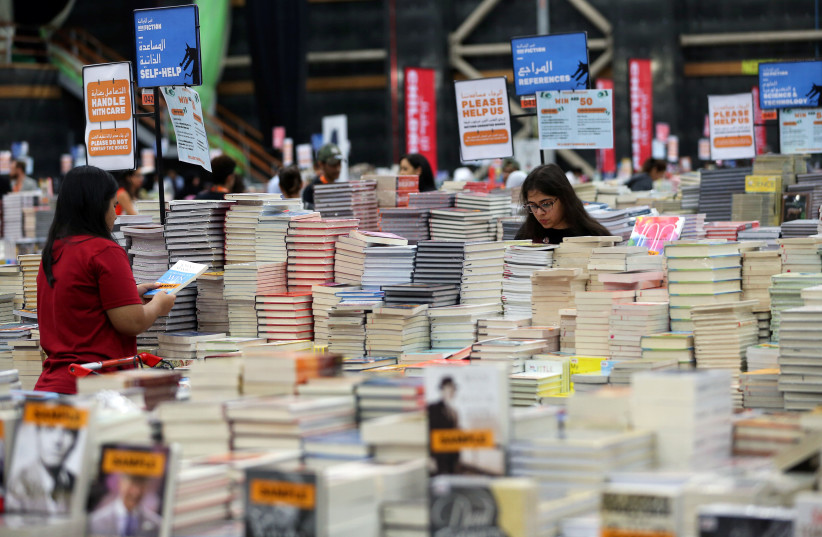 Visitors read books at the Big Bad Wolf Book Sale, which calls itself the world's biggest, hosted for the first time by Dubai, UAE October 17, 2018 (photo credit: REUTERS/SATISH KUMAR)
