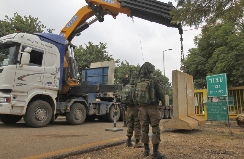a crane laying a concrete T-wall block at a security checkpoint along a road near the northern Israeli town of Metula near the border with Lebanon, December 4, 2018 (photo credit: JALAA MAREY/AFP)