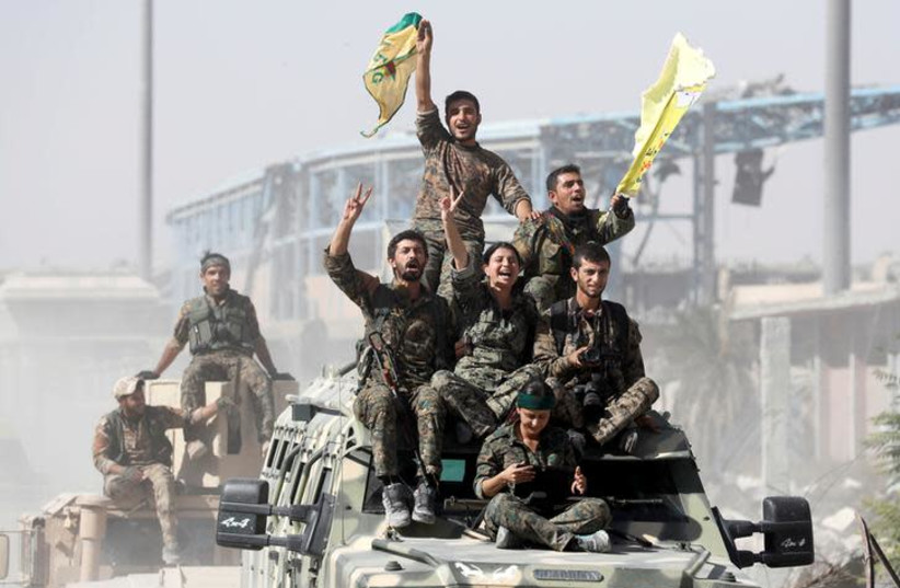  Kurdish-led militiamen ride atop military vehicles as they celebrate victory over Islamic State in Raqqa, Syria, October 17, 2017 (photo credit: REUTERS/ERIK DE CASTRO)