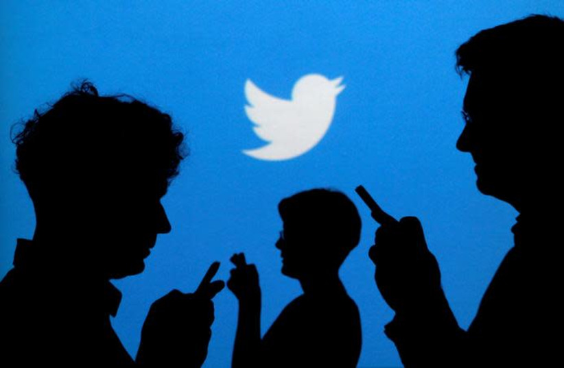 People holding mobile phones are silhouetted against a backdrop projected with the Twitter logo in this illustration picture taken September 27, 2013. (photo credit: REUTERS/KACPER PEMPEL)