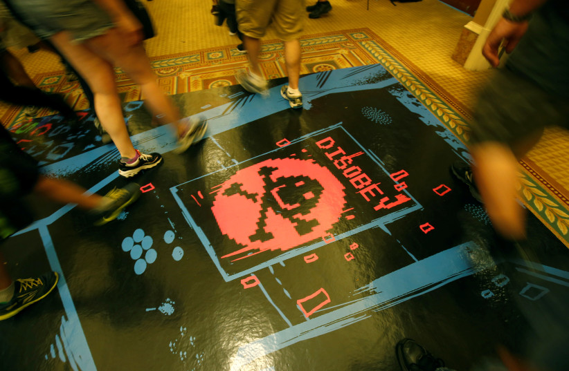 People walk past a floor graphic during the Def Con hacker convention in Las Vegas, Nevada, U.S. on July 29, 2017. (photo credit: STEVE MARCUS/REUTERS)