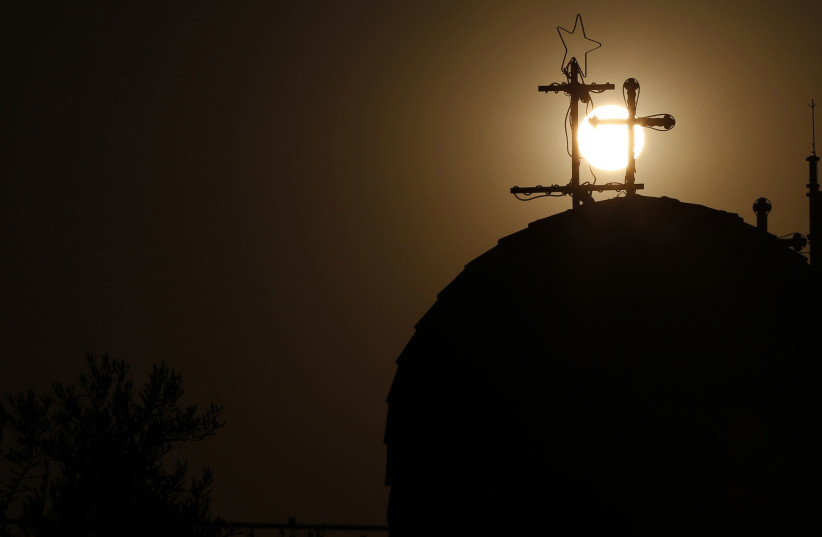 A Roman Catholic church cross is seen as the sun sets before Christians take part in a candlelight march and prayed for peace in Gaza, Jordan, and in the Arab region, in Al-Fuheis city, near Amman, August 11, 2014. Participants passed by three churches, the Roman Catholic, Greek Orthodox and Latin C (photo credit: REUTERS/MUHAMMAD HAMED)