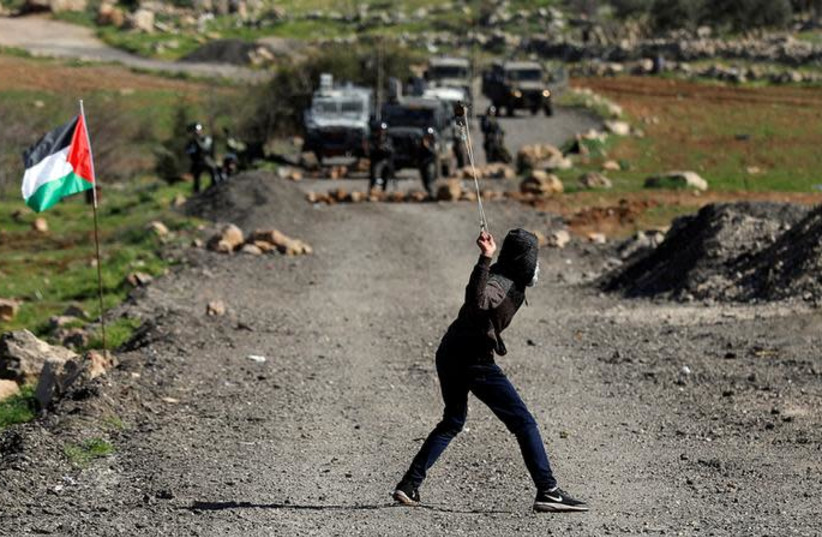 A Palestinian demonstrator uses a sling to hurl stones at Israeli troops during clashes at a protest in al-Mughayyir village near Ramallah (photo credit: REUTERS/MOHAMAD TOROKMAN)