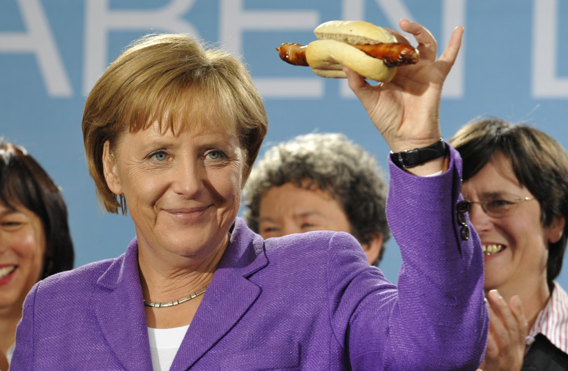 German Chancellor Angela Merkel holds up a traditional Thuringia sausage in Erfurt following an election campaign tour in the historic 'Rheingold Express' train through Germany September 15, 2009. (photo credit: WOLFGANG RATTAY / REUTERS)