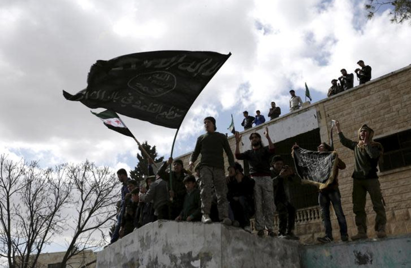 Protesters carry Al-Qaeda flags during an anti-government protest after Friday prayers in the town of Marat Numan in Idlib province, Syria (photo credit: KHALIL ASHAWI / REUTERS)
