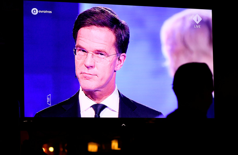 Locals sit as Dutch Prime Minister Mark Rutte of the VVD Liberal party and Dutch far-right politician Geert Wilders of the PVV party take part in the "EenVandaag" debate, shown live on television at a bar in The Hague, Netherlands March 13, 2017 (photo credit: DYLAN MARTINEZ/REUTERS)