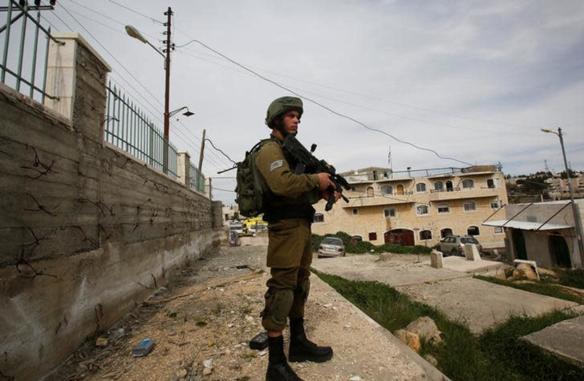 An Israeli soldier stands guard in Hebron (photo credit: REUTERS/MUSSA QAWASMA)