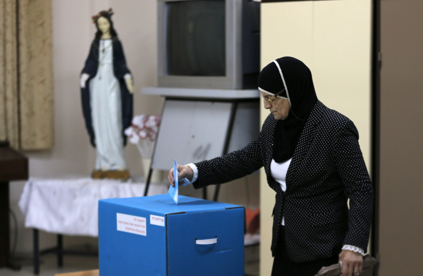 An Israeli Arab casts her ballot at a polling station inside a church in the northern town of Reineh, March 17, 2015. (photo credit: AMMAR AWAD / REUTERS)