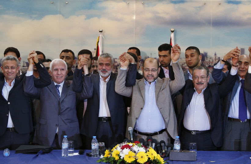Senior Fatah official Azzam Al-Ahmed (2nd L), head of the Hamas government Ismail Haniyeh (3rd L) and senior Hamas leader Moussa Abu Marzouq (4th L) , hold their hands after announcing a reconciliation agreement in Gaza City April 23, 2014. The Gaza-based Islamist group Hamas and President Mahmoud A (photo credit: SUHAIB SALEM / REUTERS)