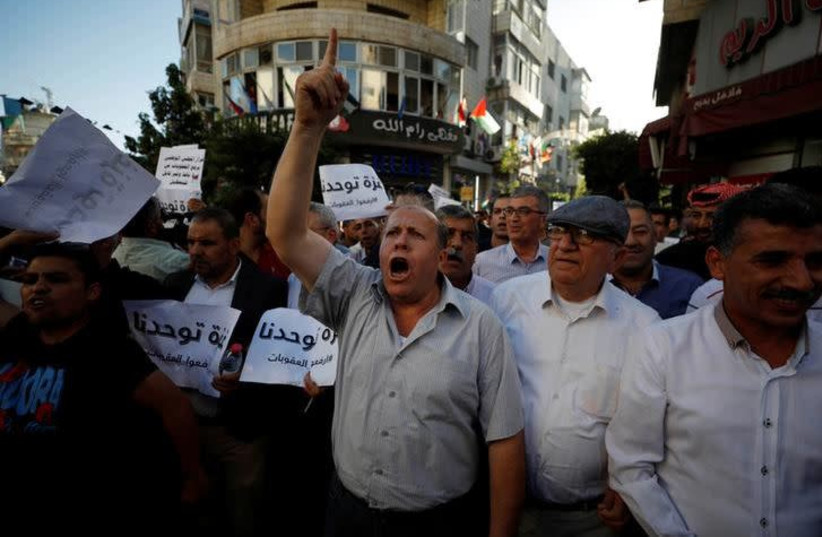 Palestinians take part in a protest calling on President Mahmoud Abbas to lift the sanctions on Gaza Strip, in Ramallah, in the occupied West Bank, June 23, 2018.  (photo credit: REUTERS/MOHAMAD TOROKMAN)