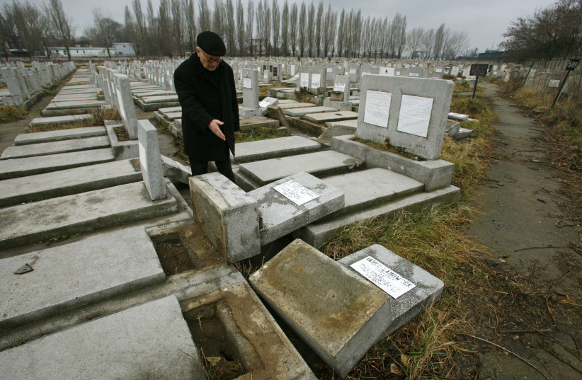 A member of Romania's Jewish community points to devastated graves at a Jewish cemetery in Bucharest February 14, 2007. Police officials said the damage was caused by children and was not part of any organised anti-Semitic activity. (photo credit: REUTERS/BOGDAN CRISTEL)
