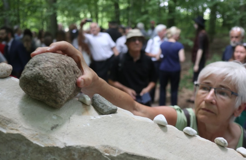 A local resident of the Polish town of Karminowice near Lublin places a stone to honor the memory of Jewish victims of the Holocaust  (photo credit: STEVEN D. REECE/ THE MATZECAH FOUNDATION)