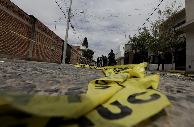 Yellow police tape lies on the road as federal agents work at a crime scene in the town in Mexico  (photo credit: ALEJANDRO ACOSTA/REUTERS)