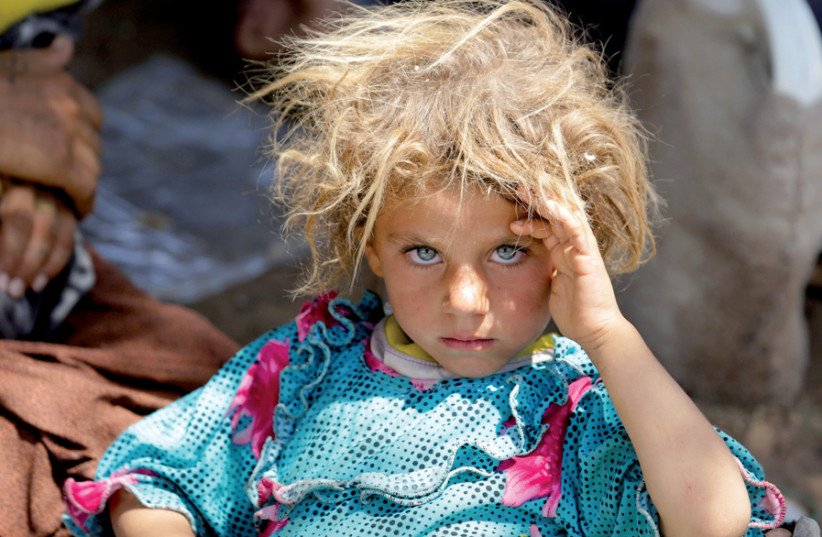 A girl from the Yazidi sect fleeing the violence in Sinjar rests at the Iraqi-Syrian border crossing in Fishkhabour, Dohuk province, in 2014 (photo credit: YOUSSEF BOUDLAL / REUTERS)