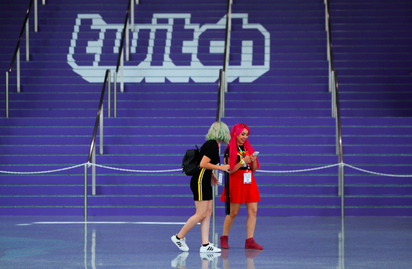 Attendees walk past a Twitch logo in Los Angeles (photo credit: REUTERS/MIKE BLAKE)