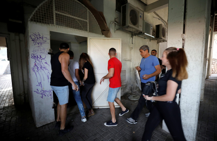People run to take shelter as a siren warning of incoming rockets sound as a spike in cross-border violence with Gaza continues, in Ashkelon, southern Israel (photo credit: AMIR COHEN/REUTERS)