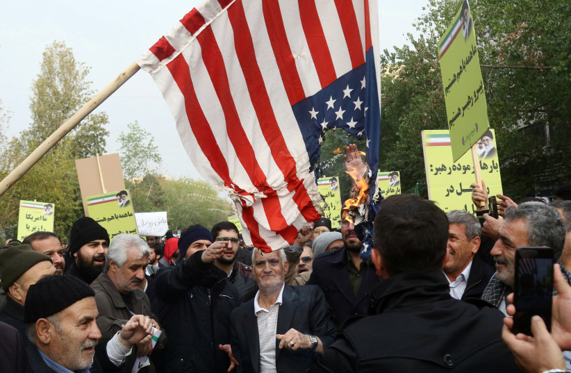 Iranian pro-government protesters burn an U.S. flag as they attend a demonstration in Tehran, Iran (photo credit: REUTERS)