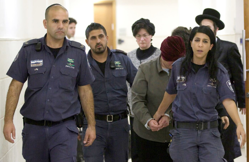 MALKA LEIFER, surrounded by Israel Prison Service guards, covers her face in Jerusalem District Court on February 14, 2018.  (photo credit: AVSHALOM SHOSHANI)