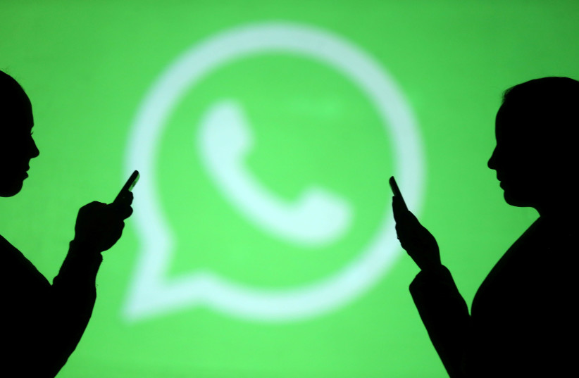 Silhouettes of mobile users are seen next to a screen projection of Whatsapp logo in this picture illustration (photo credit: REUTERS)