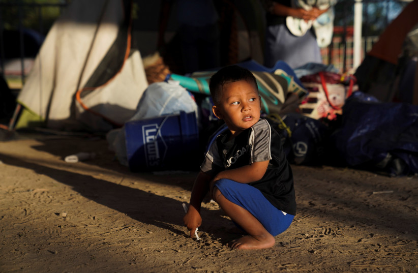 An asylum-seeking child plays in an encampment where he lives in Matamoros (photo credit: REUTERS)