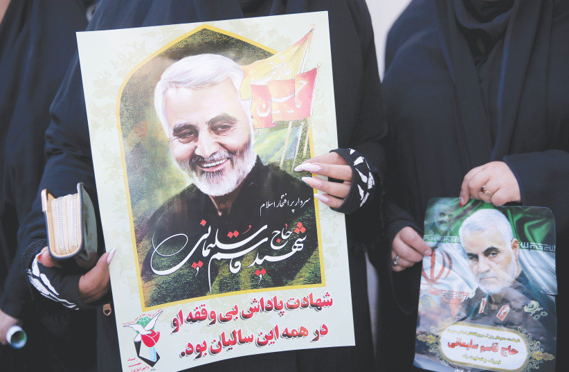 Women hold pictures of Iranian Maj.Gen. Qasem Soleimani during a funeral procession and burial in his hometown, Kerman, on Tuesday.  (photo credit: REUTERS)